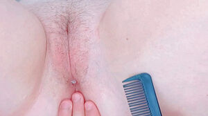 Brushing the lengthy hairs of her labia with a comb inwards