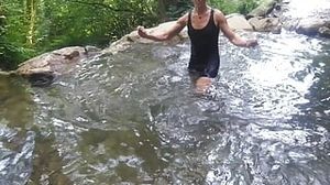Alexa Cosmic trans dame swimming in font near waterfall dressed in cutoffs and tee-shirt...