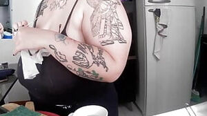 Tattoed cougar doing the dishes with too much bosom